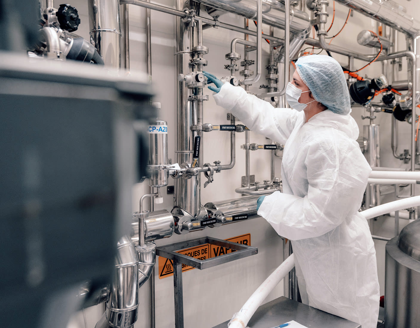 A person in a lab coat operates a complex machine, focused on their task in a laboratory setting.
